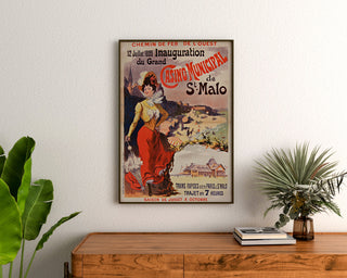 Vintage-juliste Bretagnessa – Saint-Malo, kasinon avajaiset, kehystetty puupöydän yläpuolelle, viherkasvien välissä.