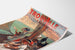 Vintagematkailujuliste Normandia – Trouville, kaupungin kasino, esitetty kaartuvalla paperilla perspektiivissä.