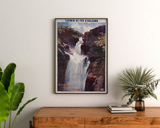 Vintagematkailujuliste – Gimel, la Grande Cascade, kehystettynä puukaapin yläpuolelle kasvien väliin.