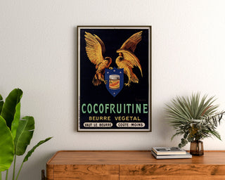 Vintage-juliste Cocofruitine, kasvirasvavoi, kehystetty puukaapin yläpuolelle kasvien väliin.