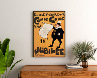Vintage-juliste Dudley Hardy, Comic Guide, kehystettynä puupöydän yläpuolella kasvien välissä.