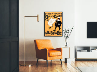 Vintage-juliste Dudley Hardy, Comic Guide, kehystettynä olohuoneessa oranssin nojatuolin ja lattiavalaisimen kanssa.