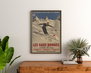 Vintage-juliste Les Eaux-Bonnes, talviurheilu, kehystettynä puukomodin yläpuolelle kasvien väliin.