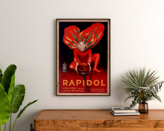 Vintage-juliste Rapidol, kehystetty puisennon lipaston yläpuolelle kasvien väliin.