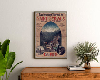 Vintagetyylinen Saint-Gervais, kylpylälaitos -juliste, kehystettynä puukomodin yläpuolella kasvien ympäröimänä.