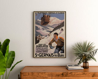 Vintagetyylinen Saint-Gervais, Mont-d’Arbois -juliste, kehystettynä puukomodin yläpuolella kasvien ympäröimänä.